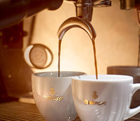 Espresso läuft aus Siebträgermaschine in zwei Dallmayr Espressotassen