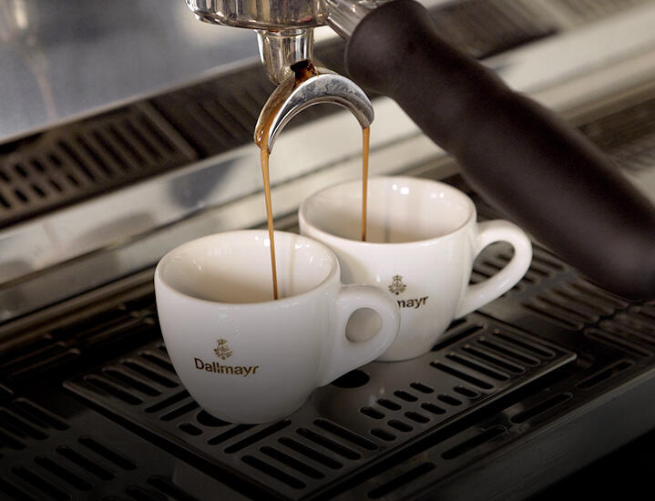 Frisch gebrühter Espresso läuft aus einer Siebträgermaschine in Dallmayr Espresso Tassen