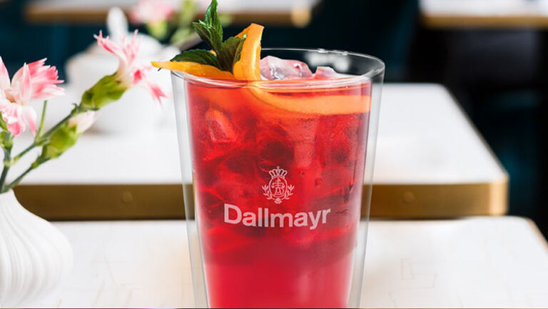 Ľadový čaj Dallmayr v pohári ozdobenom pomarančom a mätou