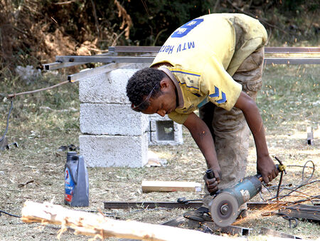 Etiopijos darbininkas pjauna metalinius strypus